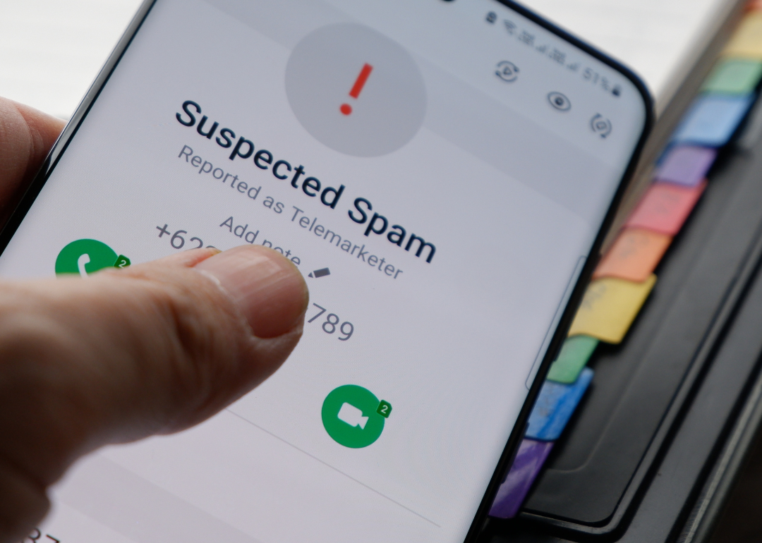 A close-up of someone's hand holding a phone while receiving a spam call.