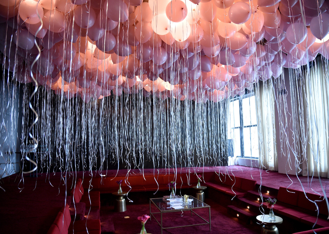 Many pink balloons hanging from a ceiling for a party.