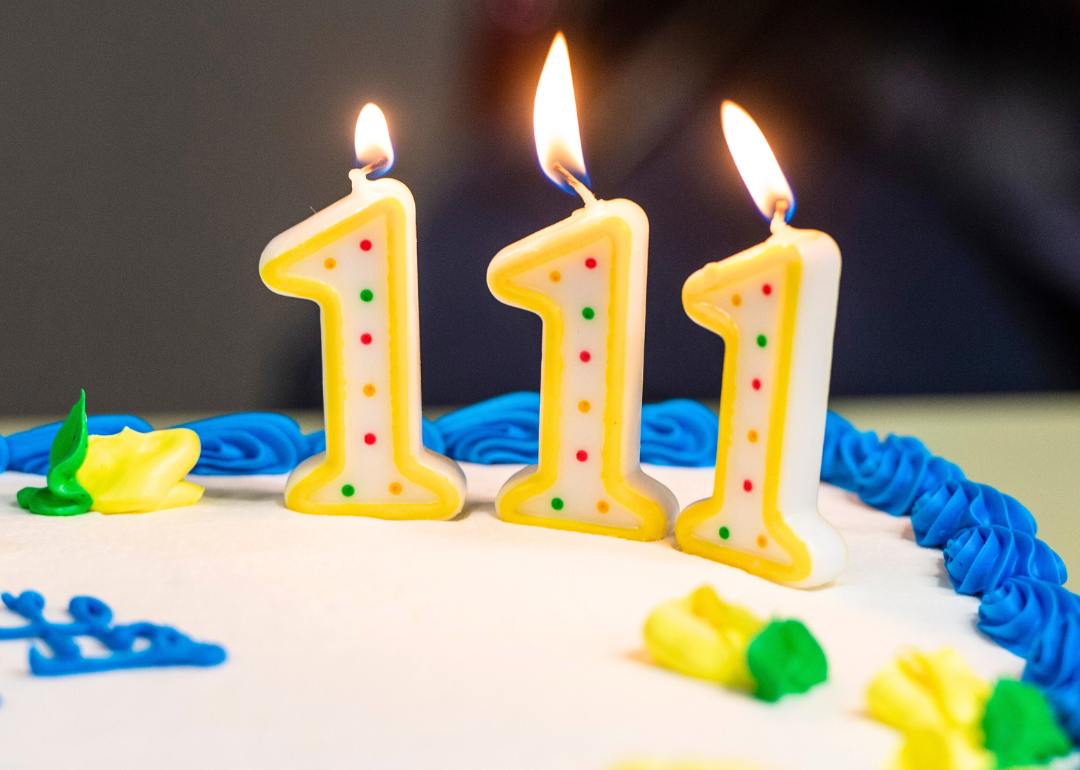 A 111-year-old's birthday cake with three lit number one candles.