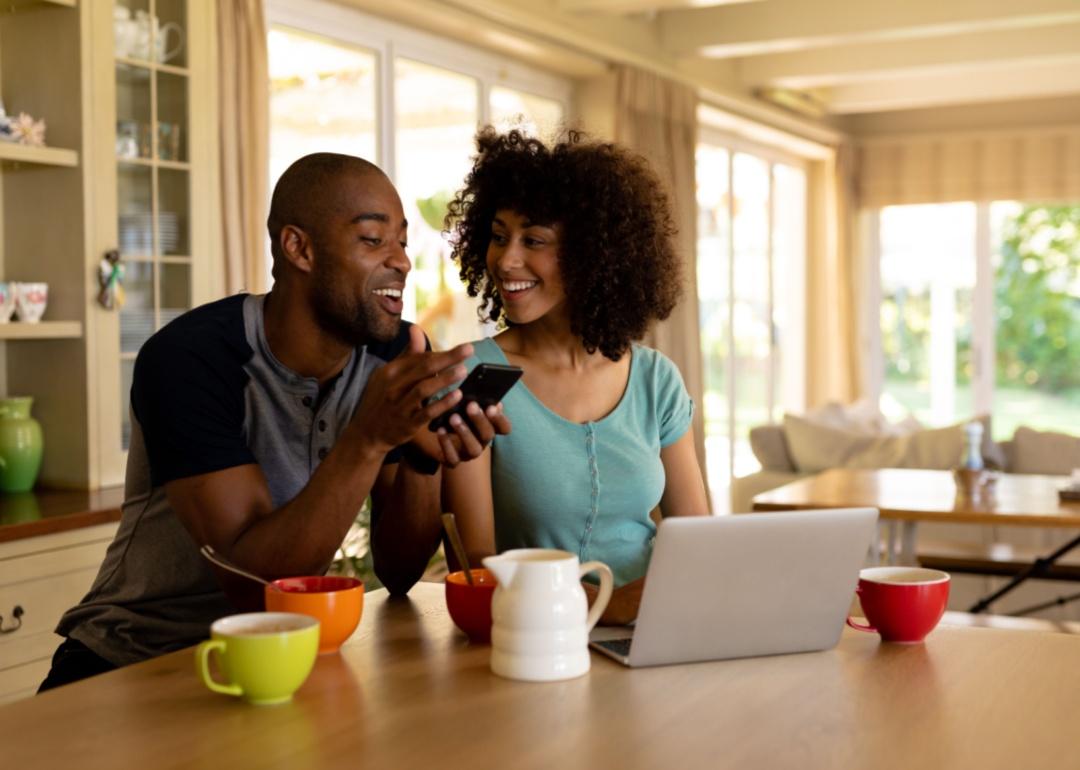 A couple on a cellphone in the kitchen.