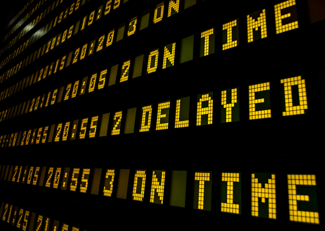 A black sign with yellow lettering showing flight delays.