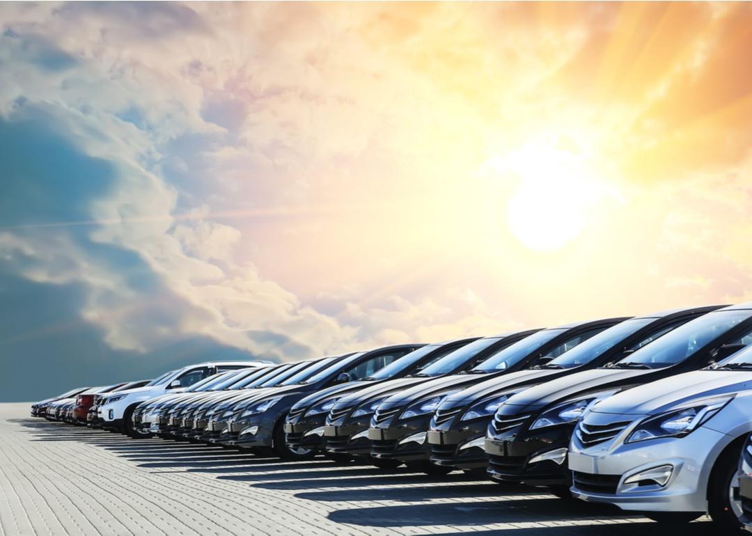 Row of cars at dealership with beautiful sky in background.