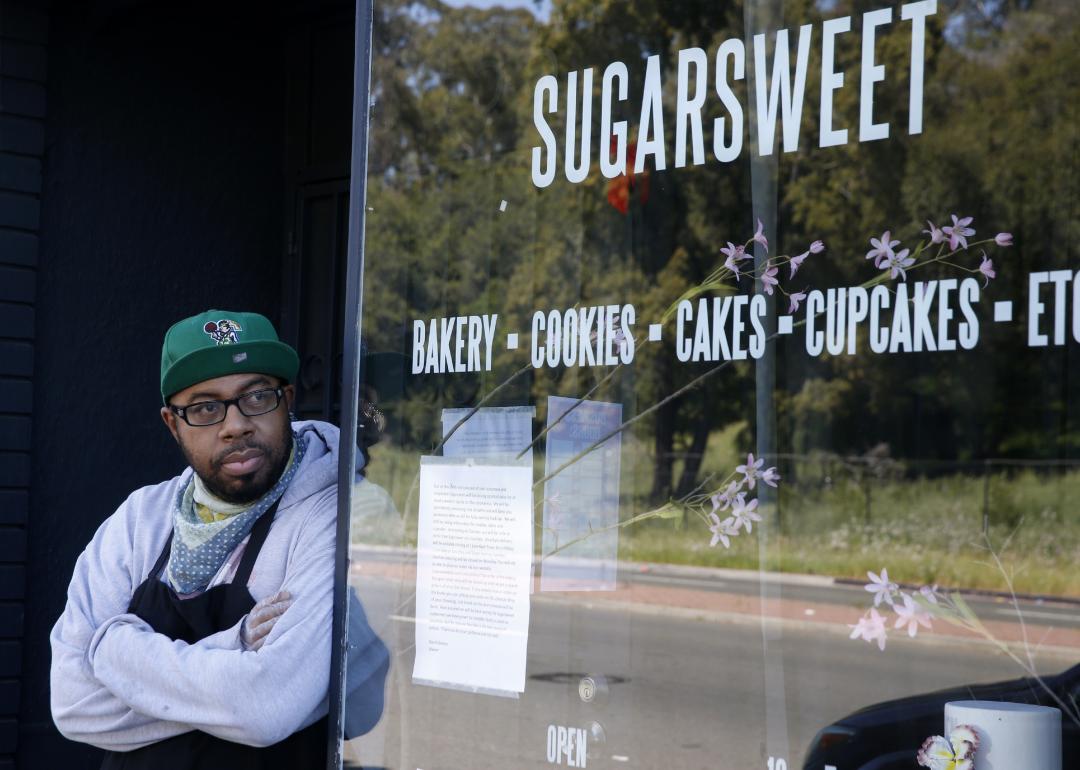 Business owner leaning against the wall outside at his Sugarsweet Cake and Cookie Studio.
