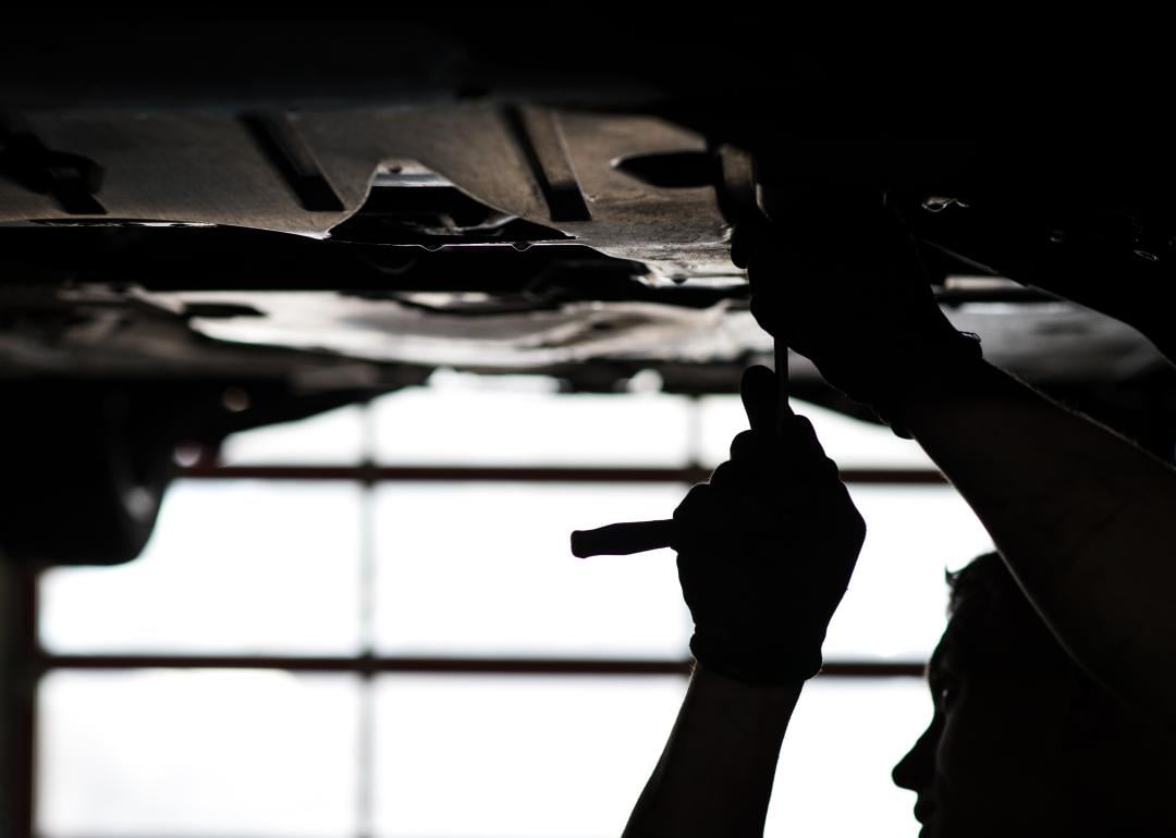 A person repairing a vehicle on a lift.