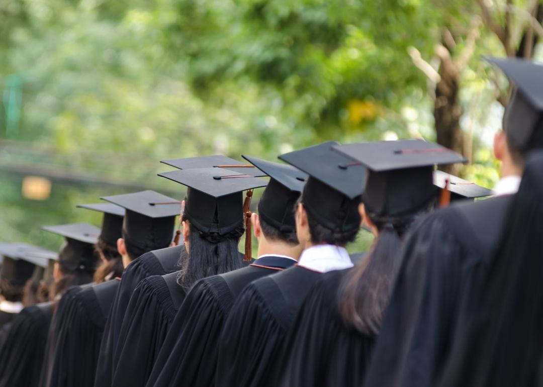 College graduates in black caps and gowns in a line.
