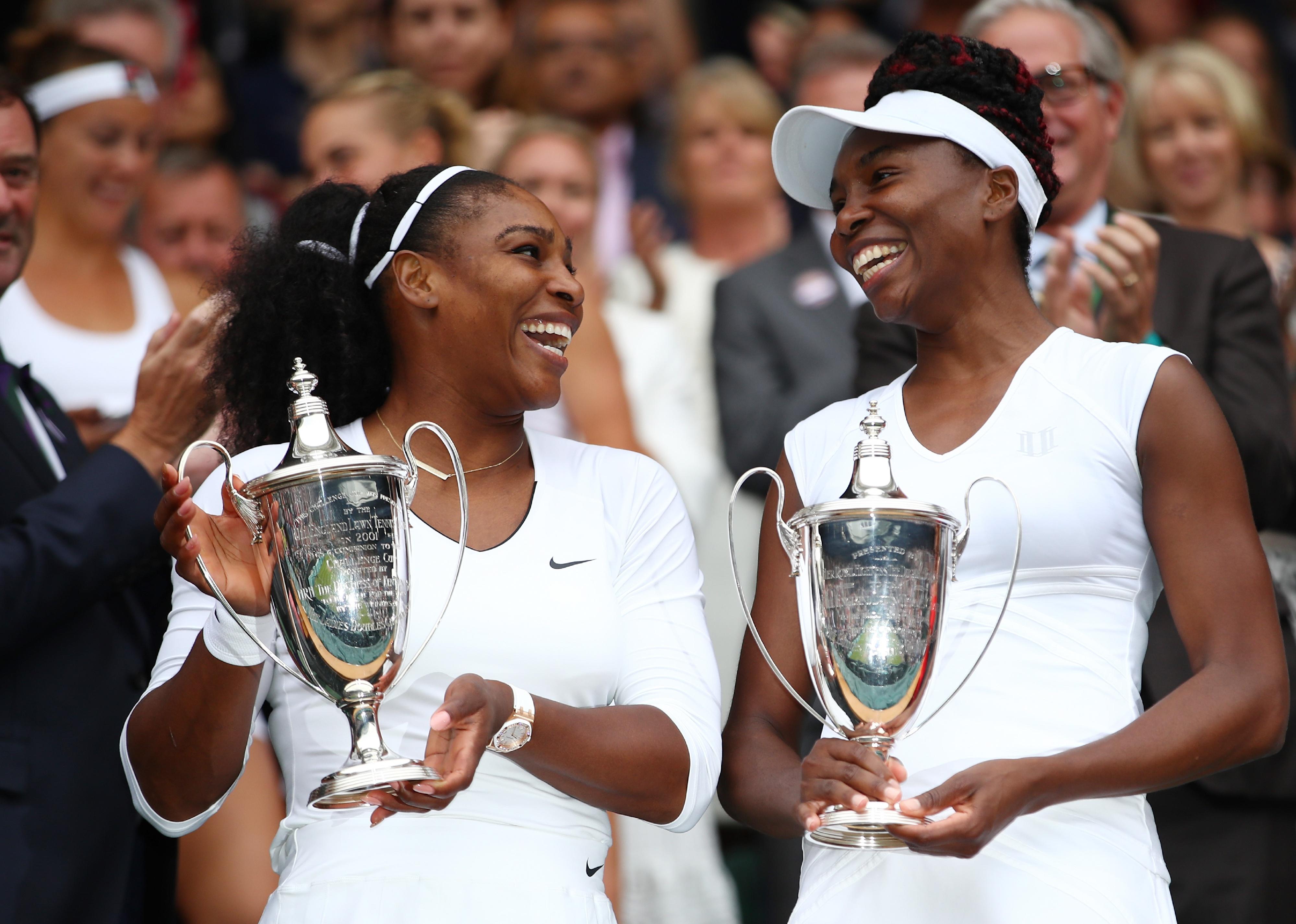 Venus Williams and Serena Williams hold up their trophies following victory in the Ladies Doubles Final