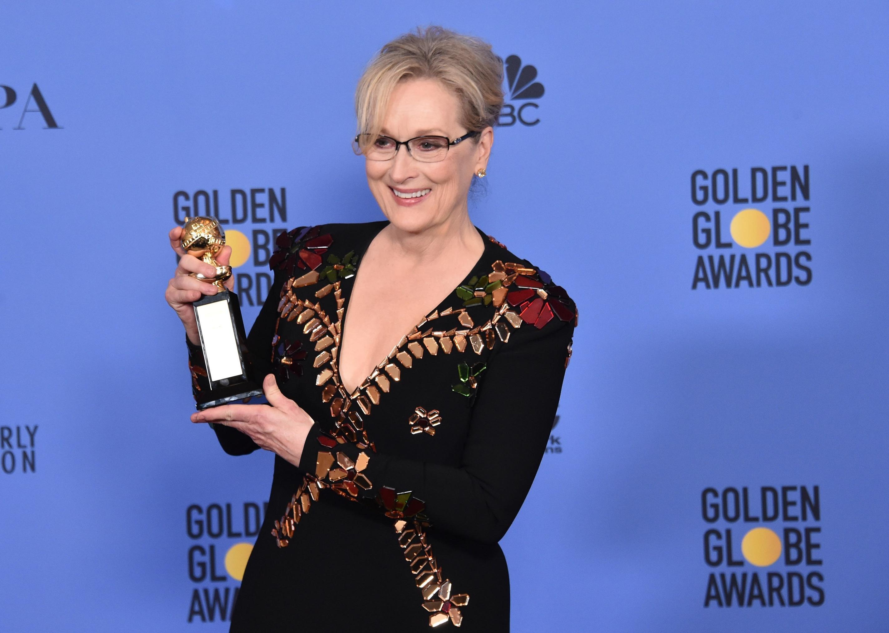 Meryl Streep smiling, holding her Golden Globe.