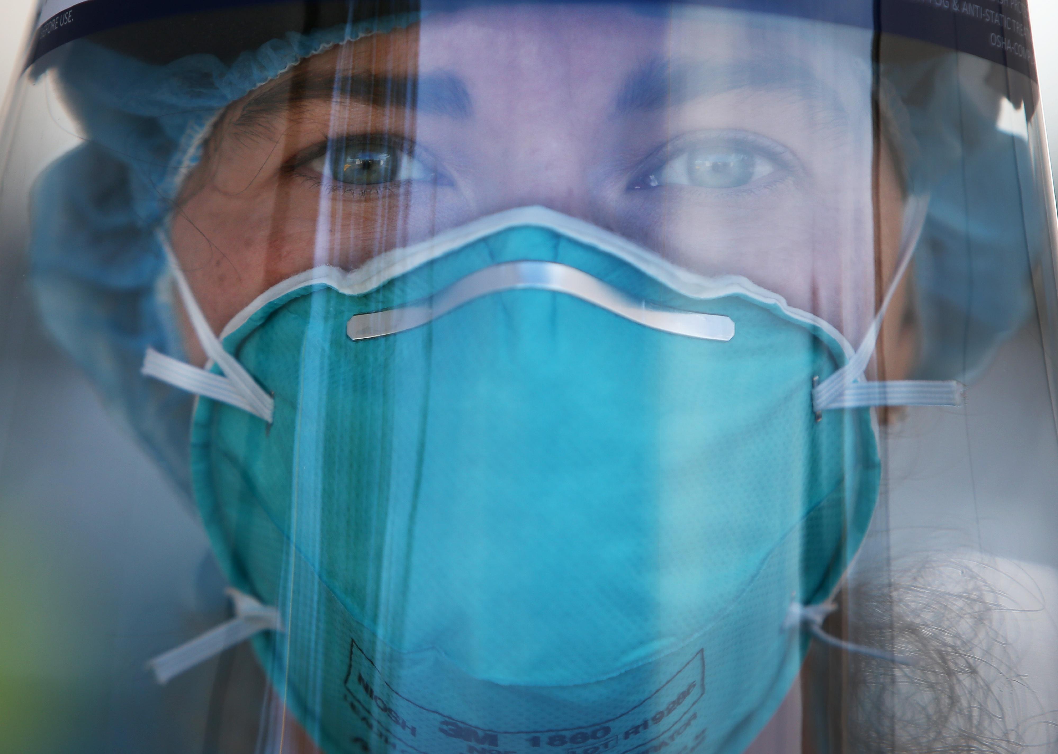 A nurse with an intense look on her face wearing protective gear.