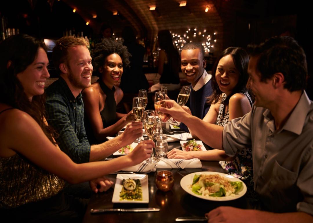 A group of friends toast each other at a restaurant.