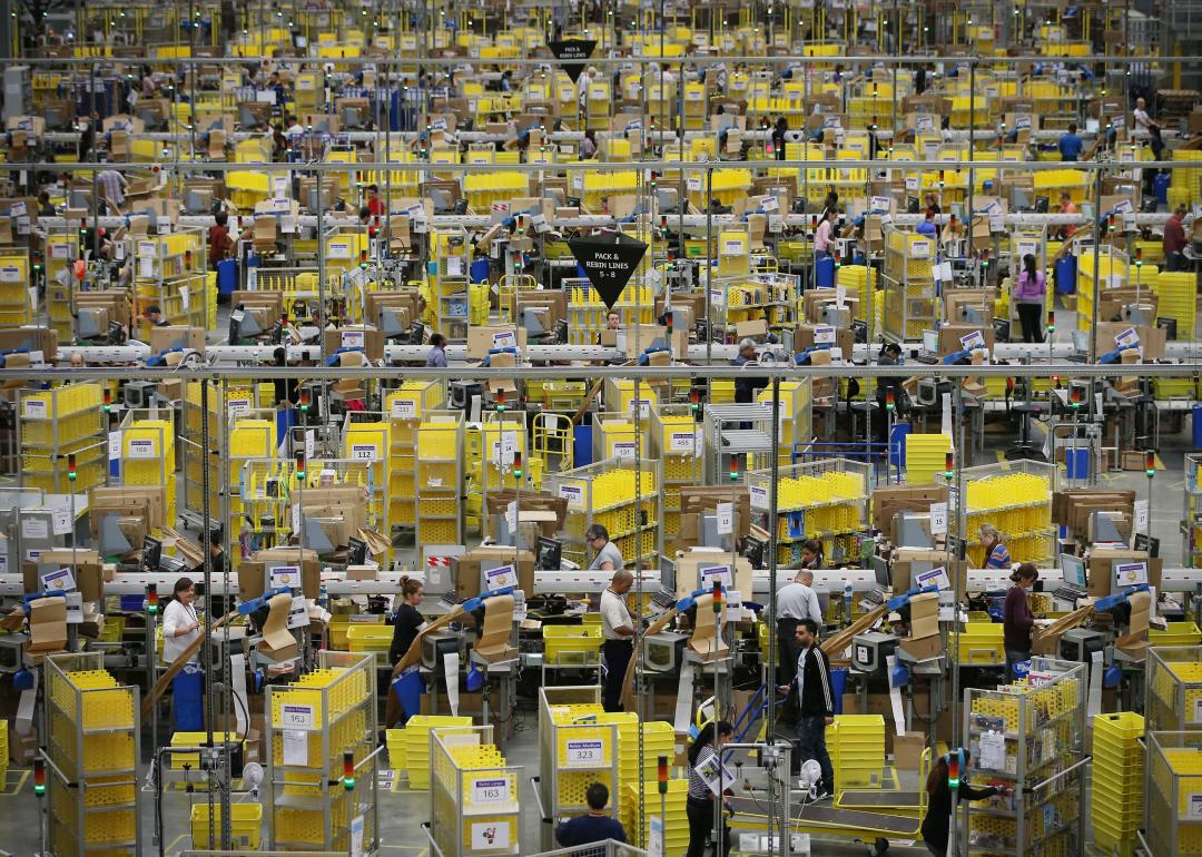 Workers in rows in a large amazon warehouse.
