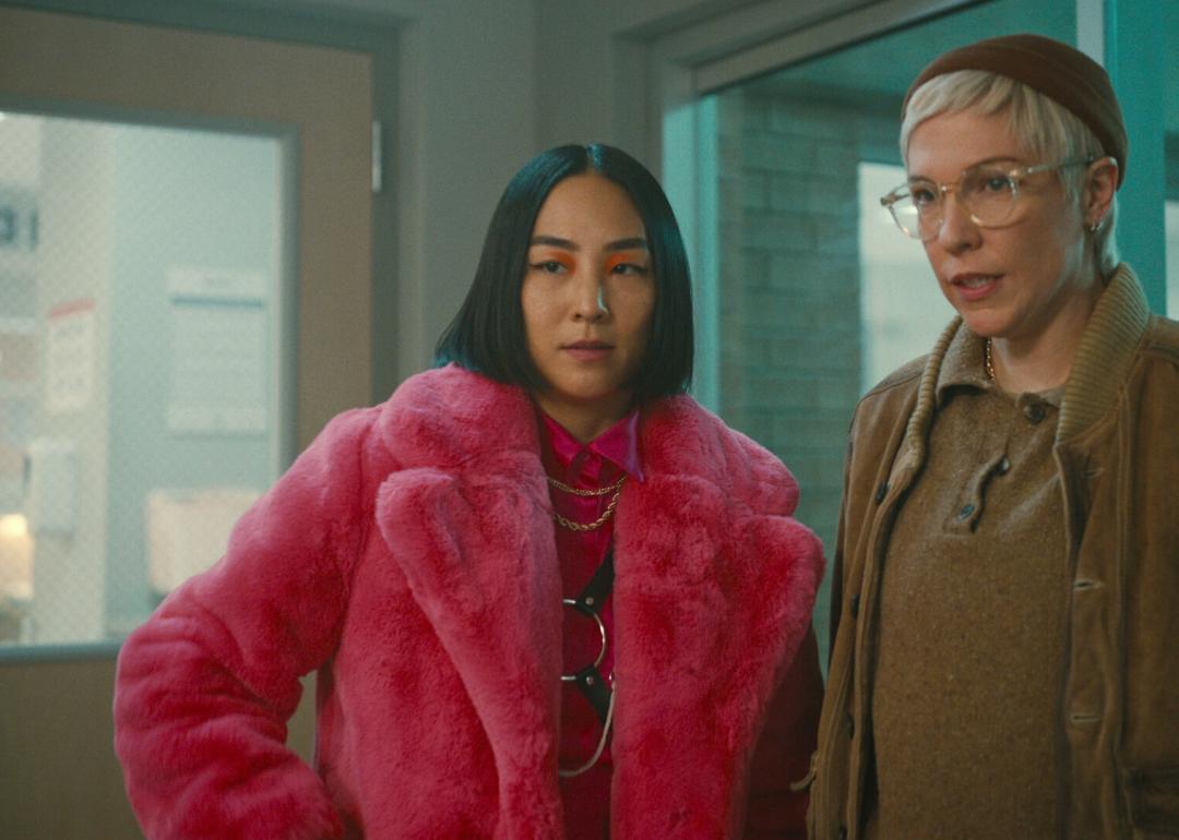 Two women looking skeptical, one in a pink fur coat.