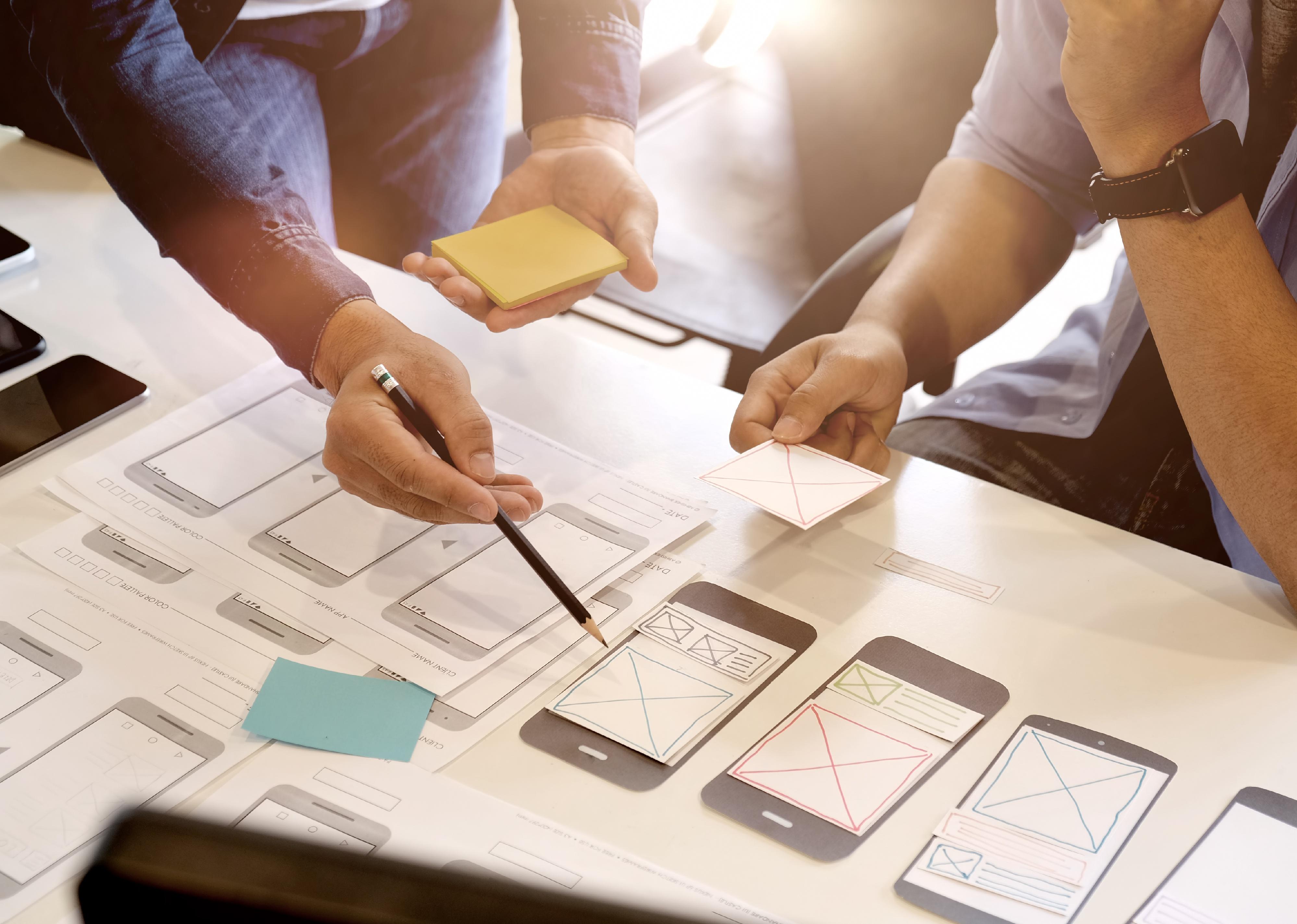 Two people working on smart phone app layout.