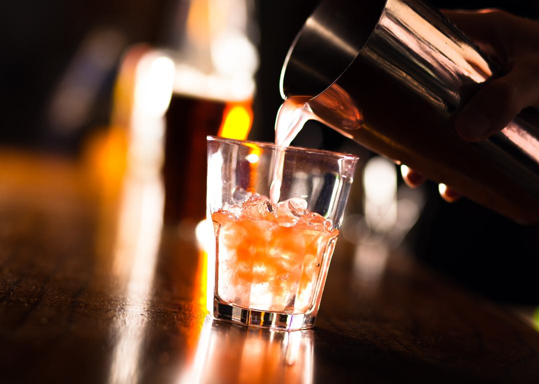 Barman pouring a cocktail into a glass.