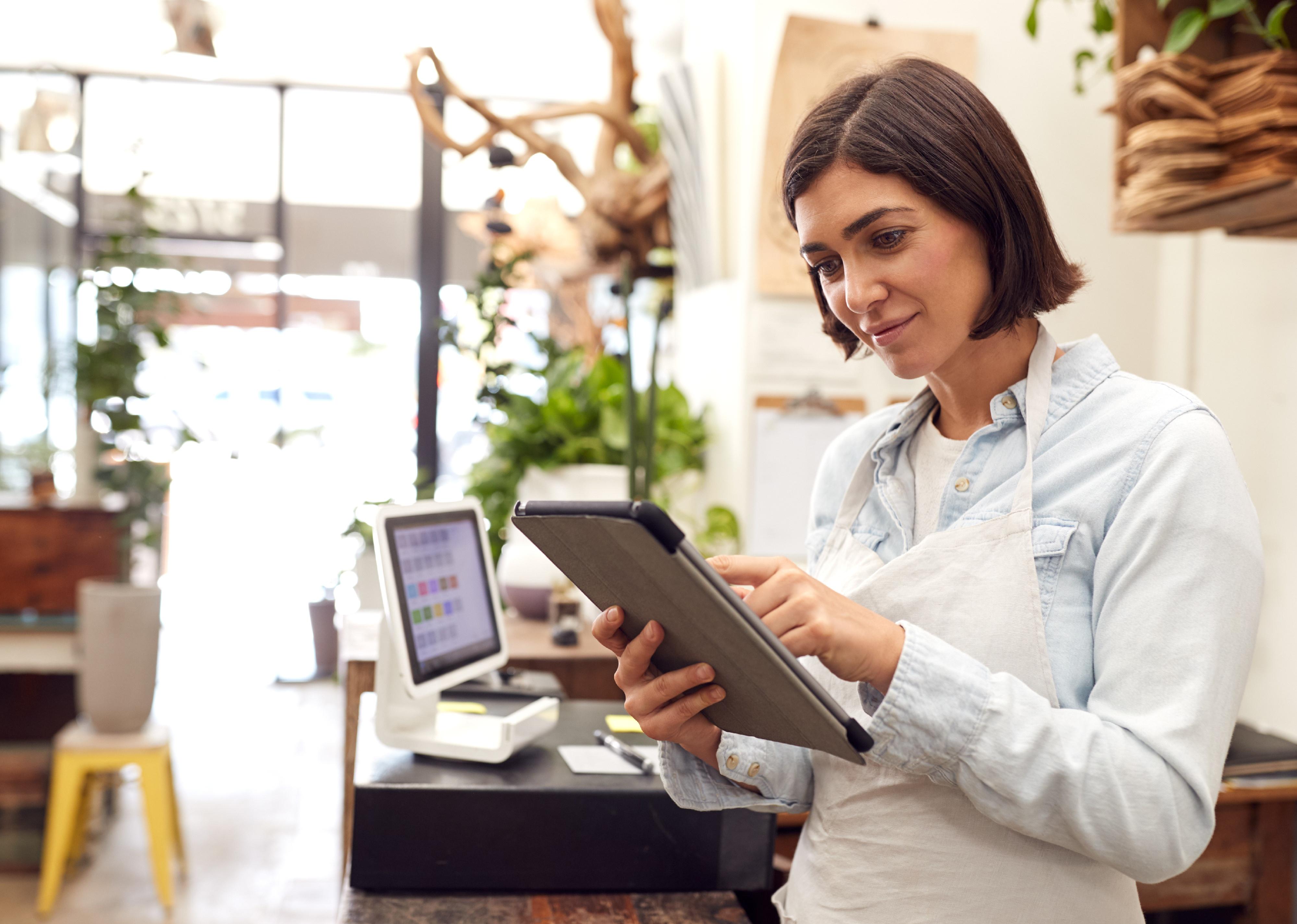 Female with tablet behind sales desk of florist store