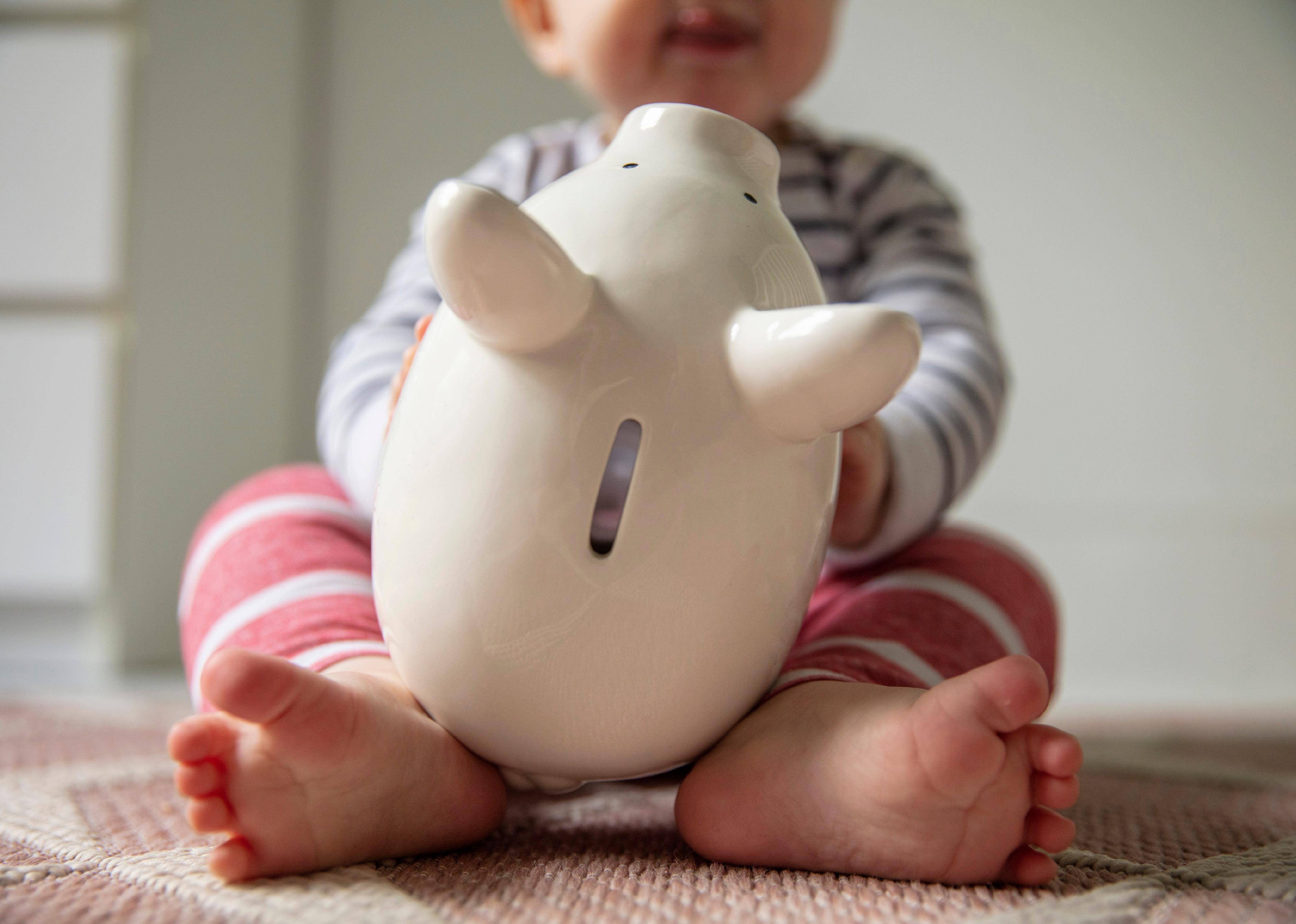 Young baby playing with a piggy bank.
