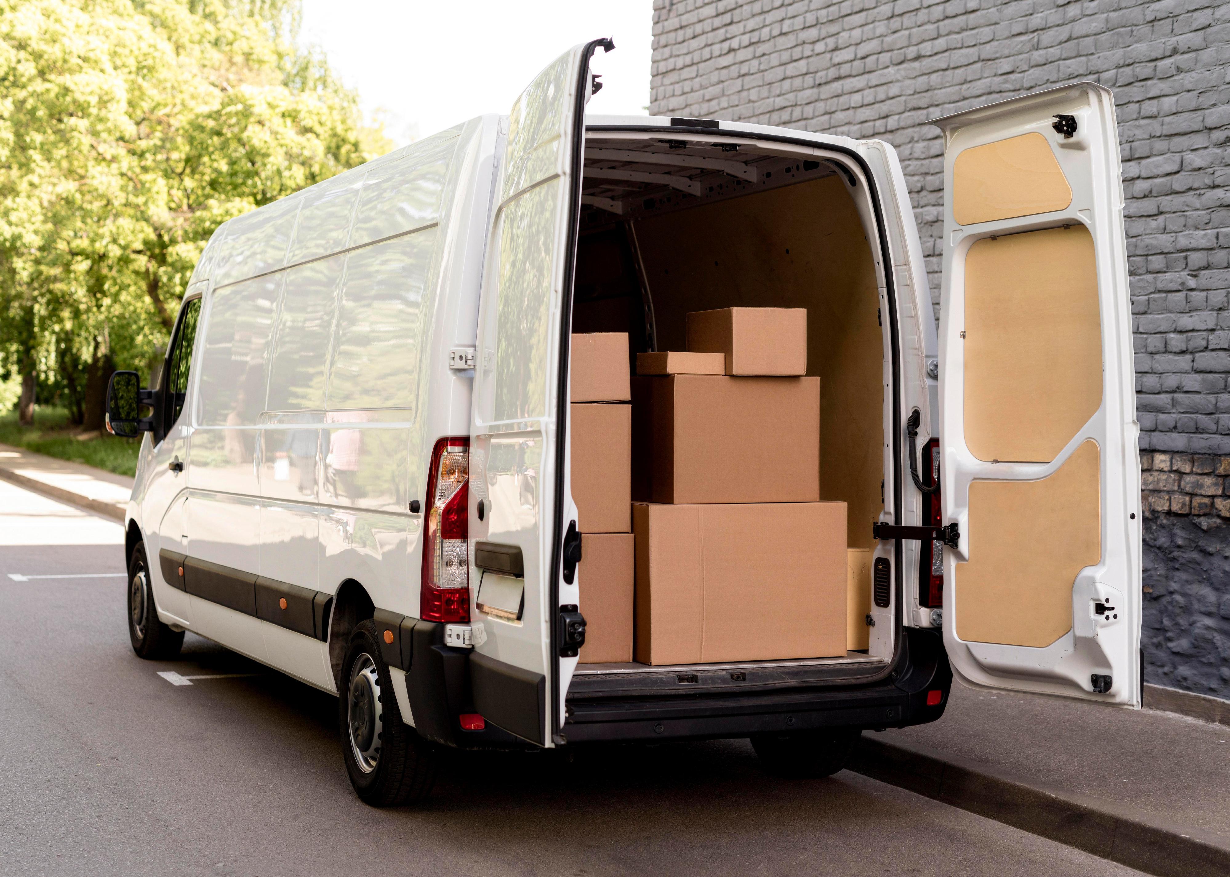 White van with its back doors open, showing the back full of cardboard boxes.