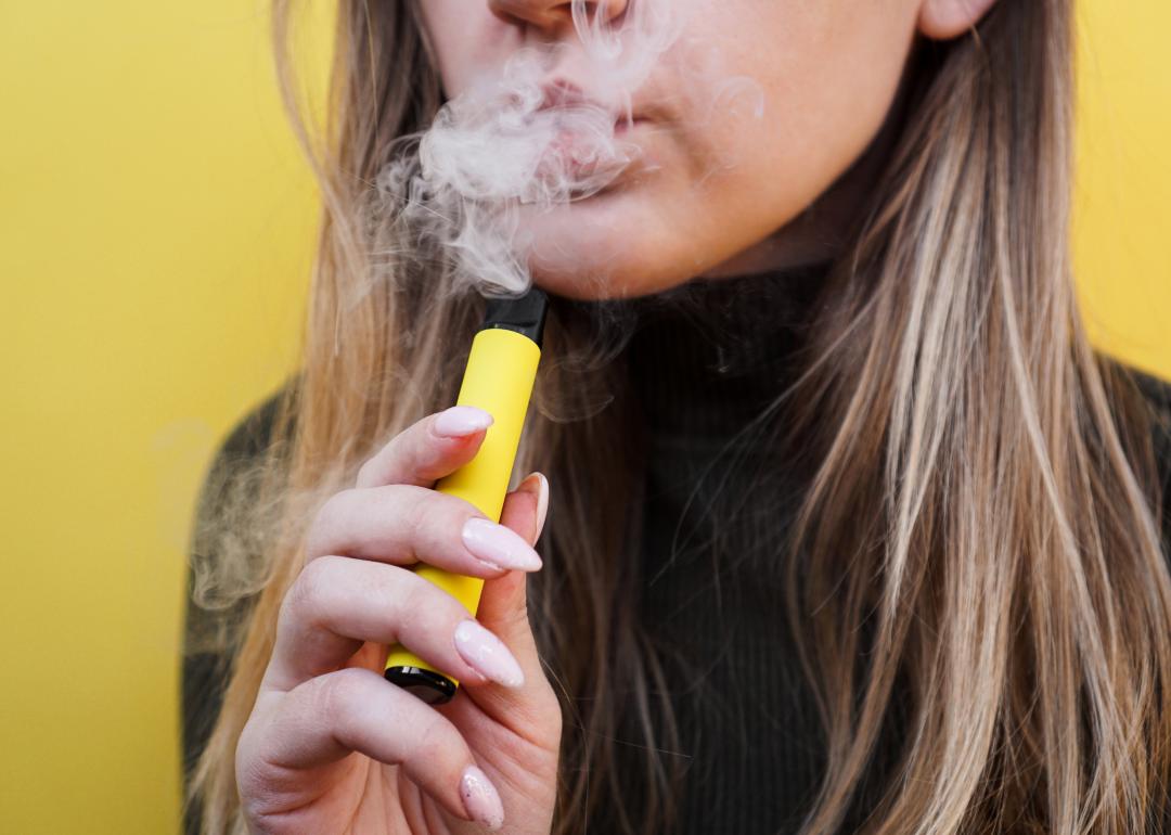 A young woman uses a disposable electronic cigarette.