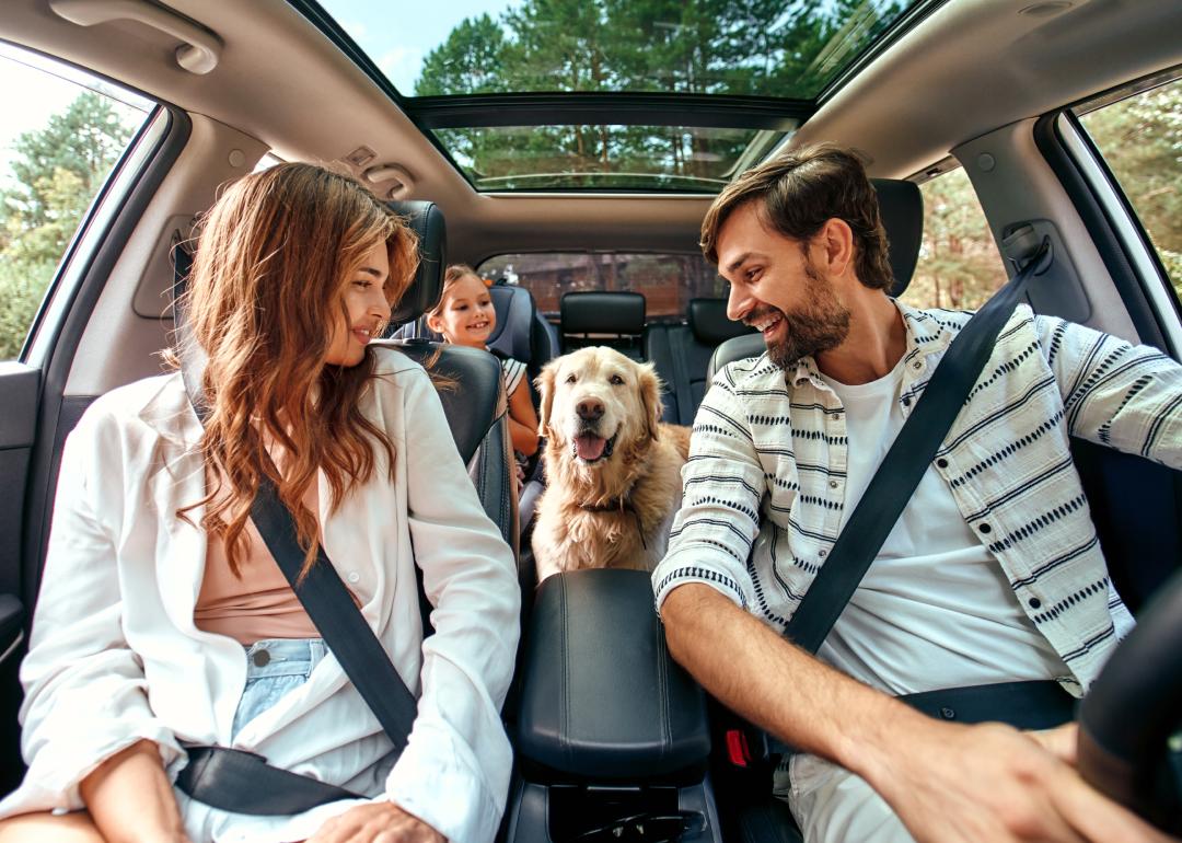 A family and a Labrador dog sitting in a car. 