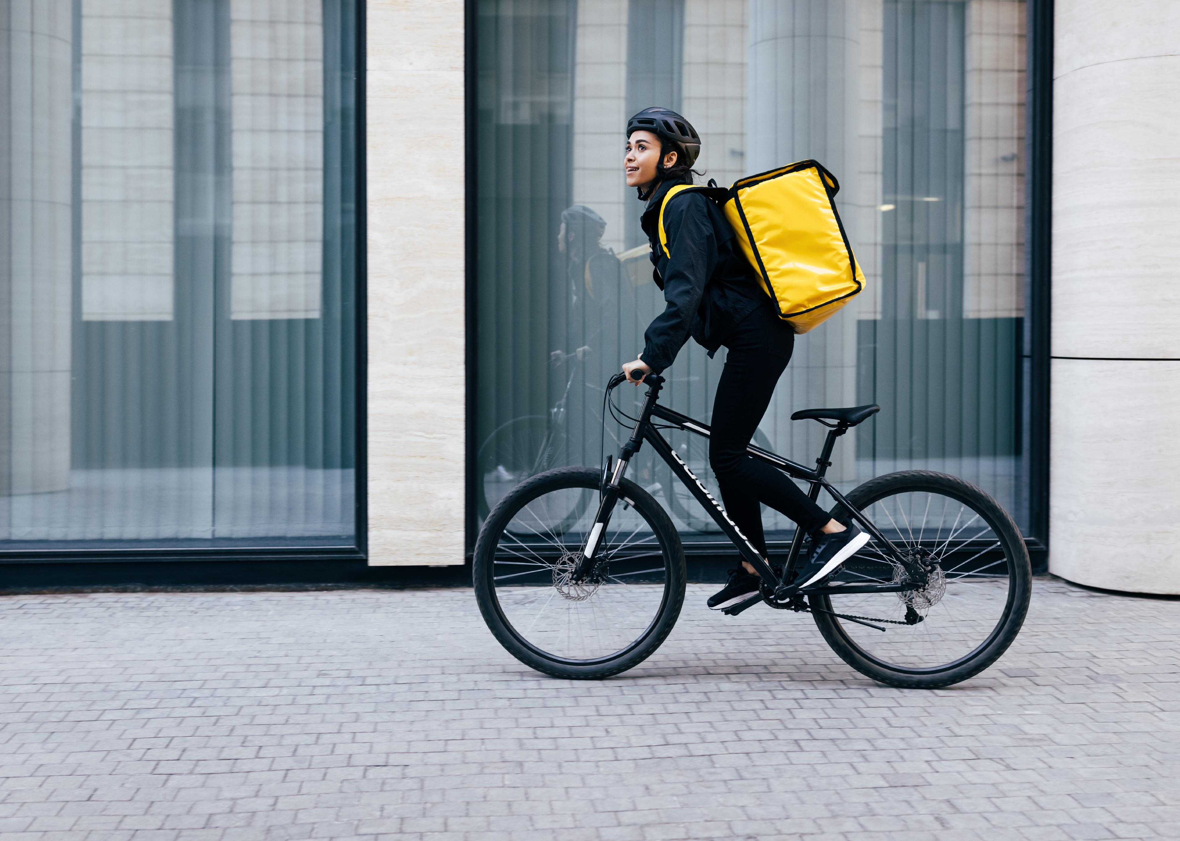 Side view of a young woman riding her bike in a city.