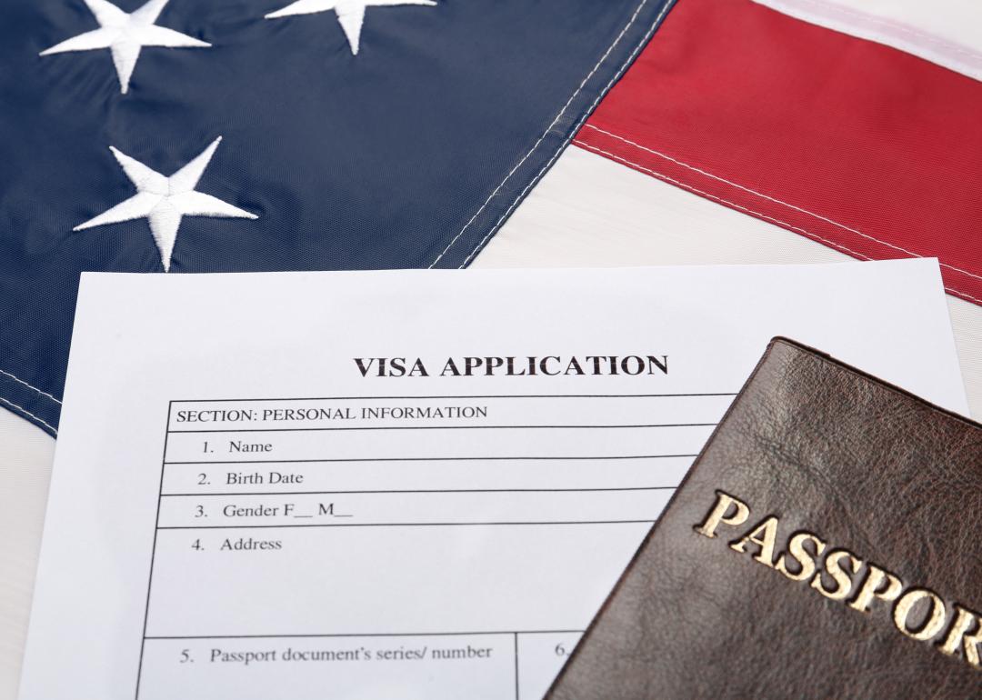 Visa application form and passport on American flag.