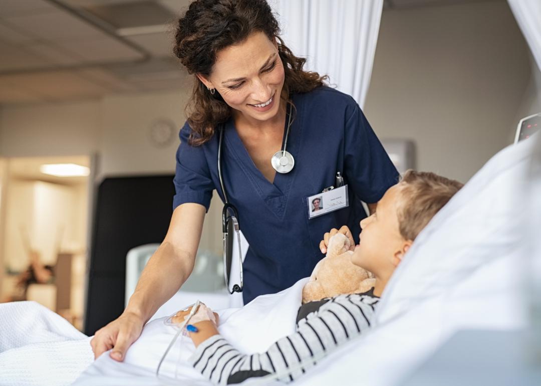 A nurse taking care of little boy hospitalized in a bed.