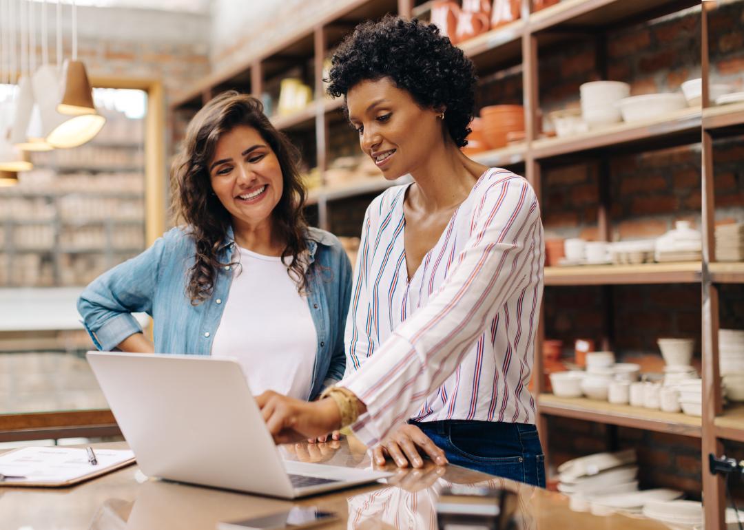 Two women ceramists using a laptop while working together.