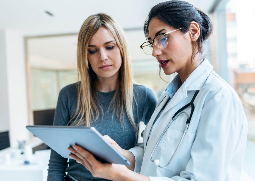 A doctor holding a tablet, speaking with a patient.