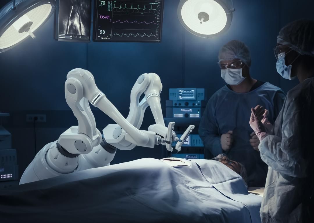 Two surgeons observing a robotic arm during operation.