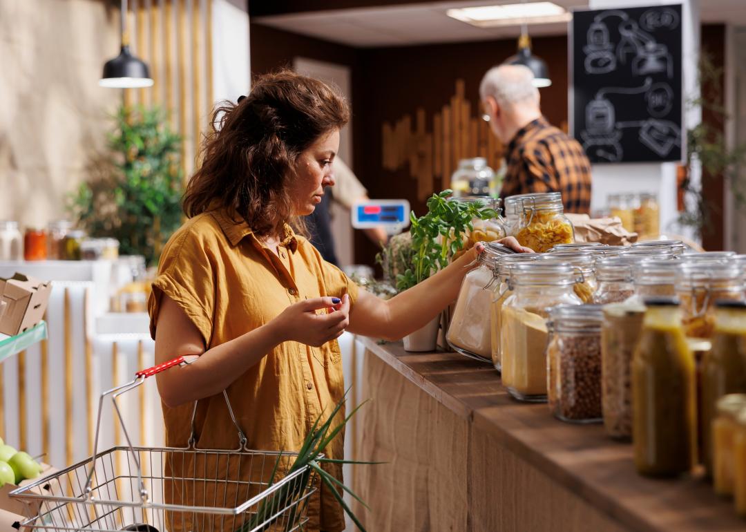 Woman in a zero waste store looking at jars of dried goods.