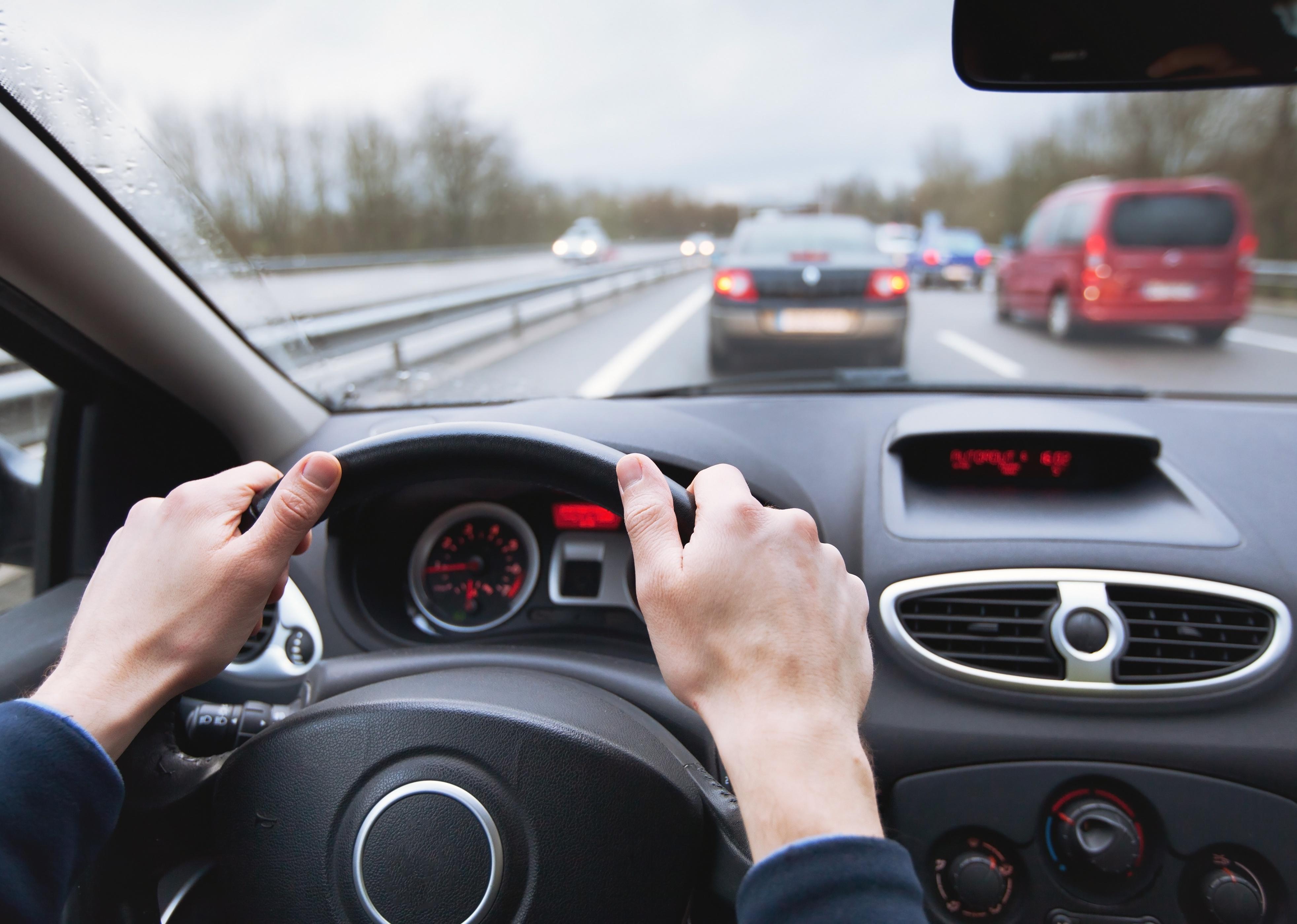 Close-up of hands on a steering wheel.