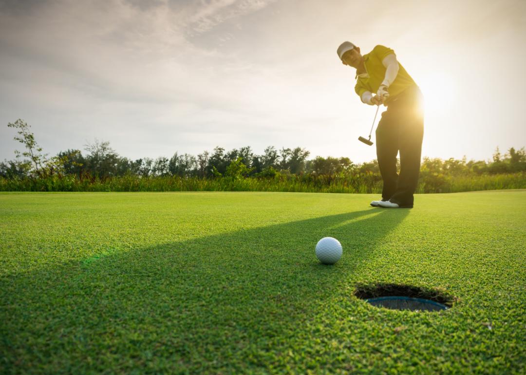 Golfer putting golf ball on the green.