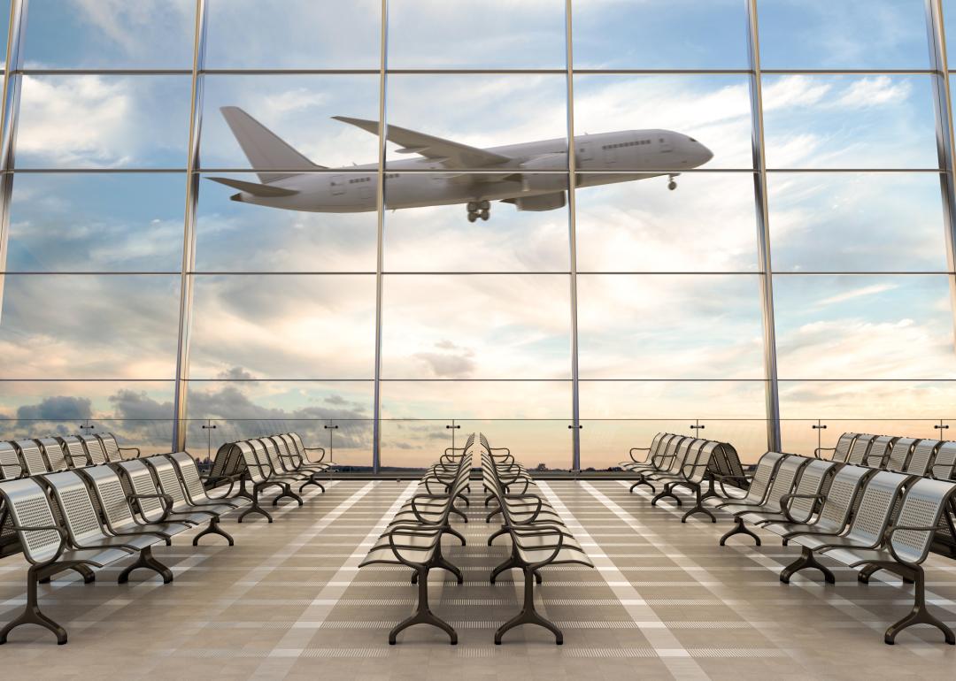 Empty airport terminal lounge with airplane on background. 