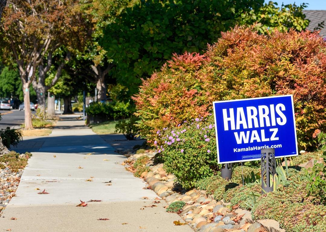 Harris-Walz yard lawn sign in a residential garden near a sidewalk in California.