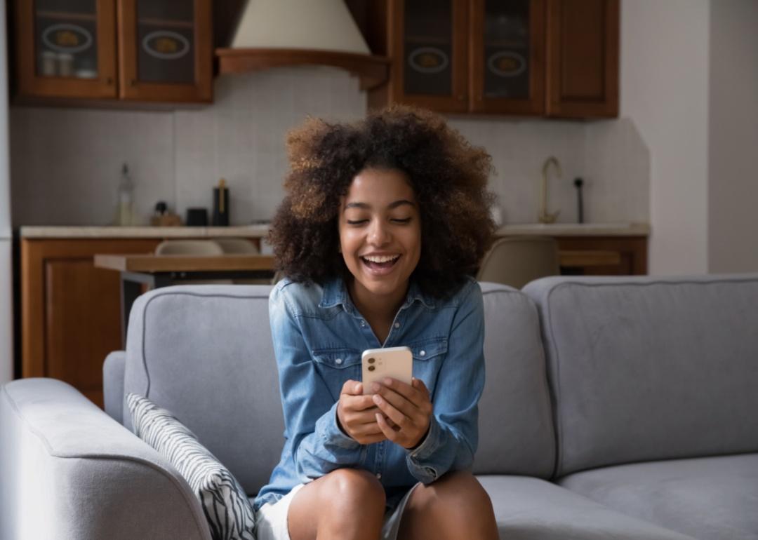 A girl laughing while looking at a phone.