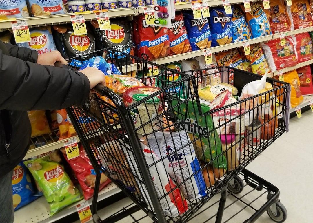 Pushing a cart filled with groceries on the snacks aisle inside a supermarket in Wilmington, Delaware.