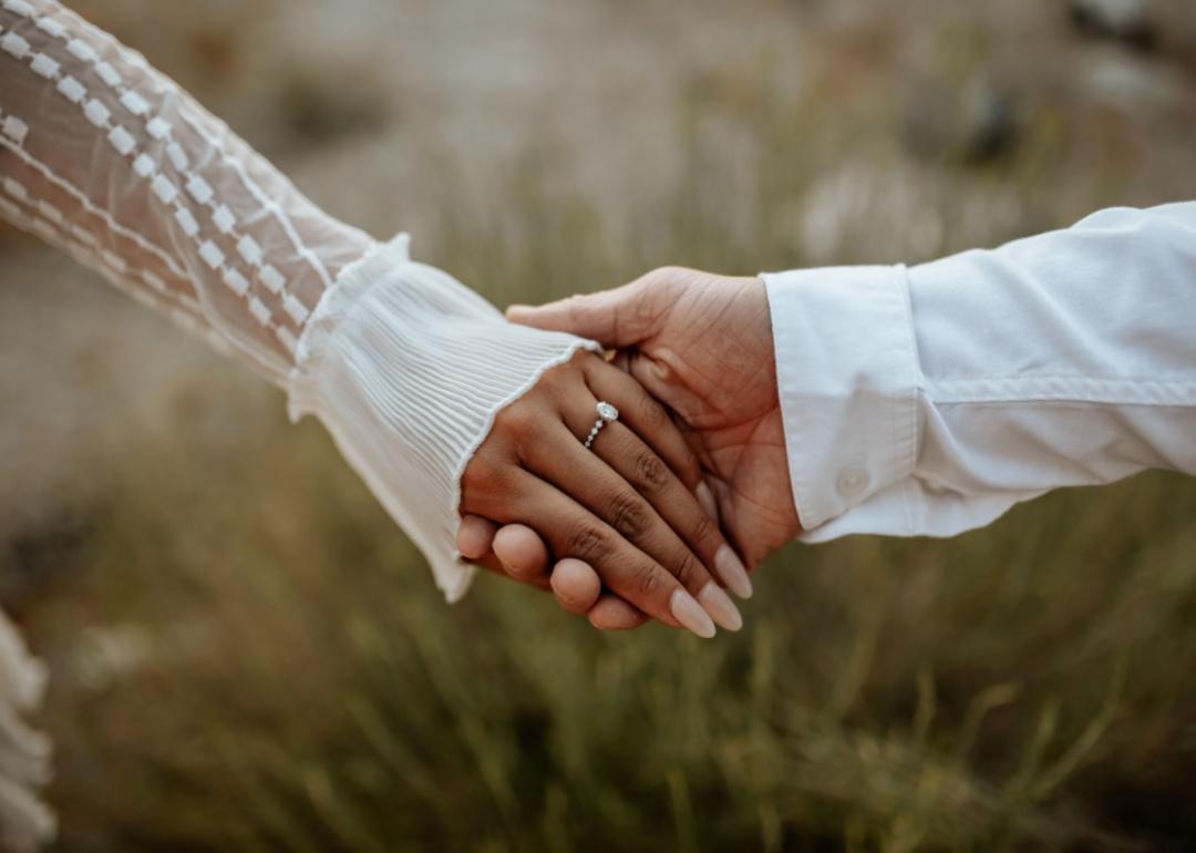 Two people holding hands in wedding attire.