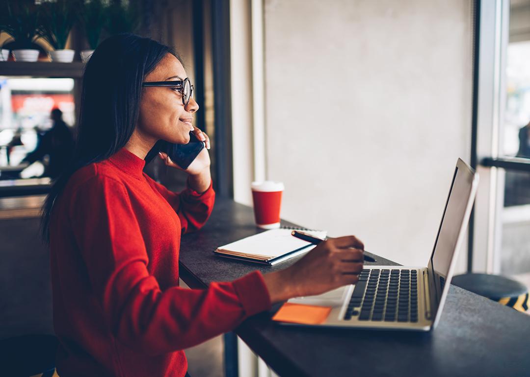 A professional copywriter taking a phone call while working with a laptop in a cafe.