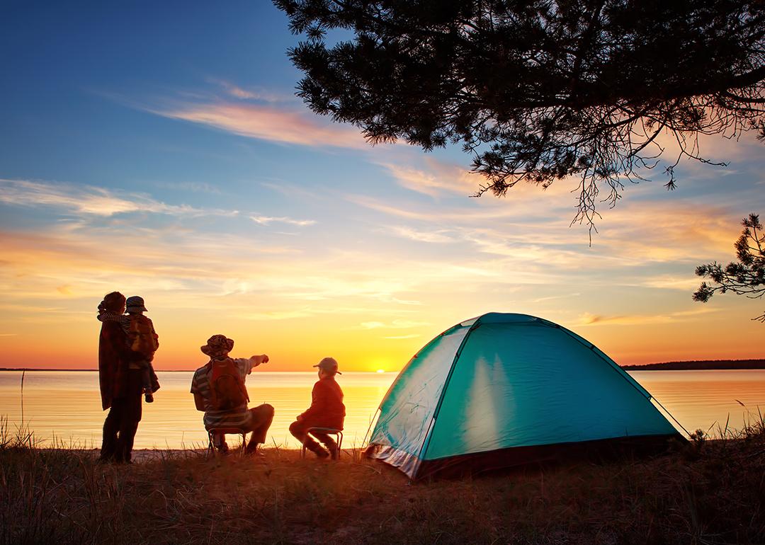 Family of four set up camp near the lake and watching the sunset.