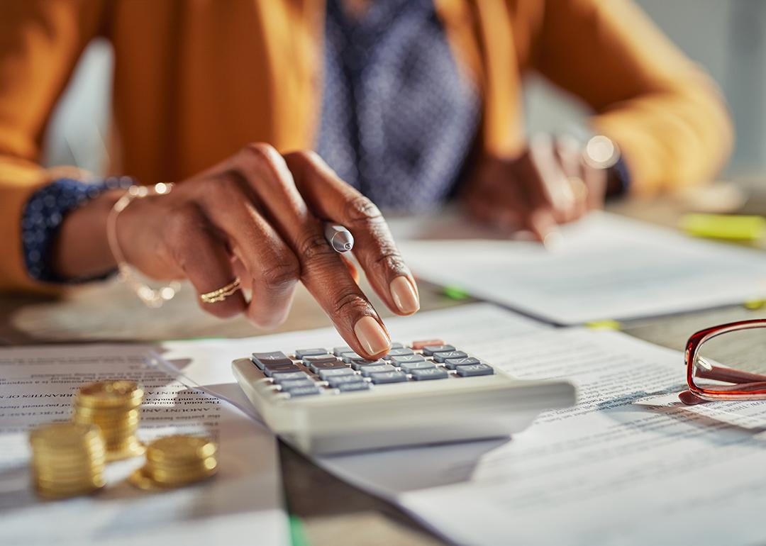 Tax professional using a calculator while reviewing finance documents.