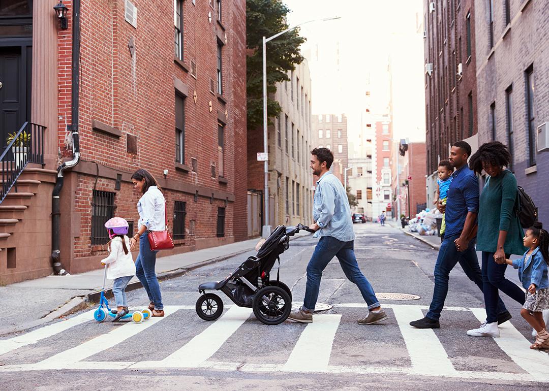 Two families crossing a road along an apartment neighborhood.