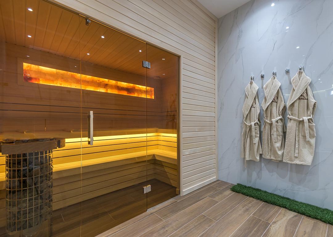 A modern home sauna with bathrobes hanging on its wall.
