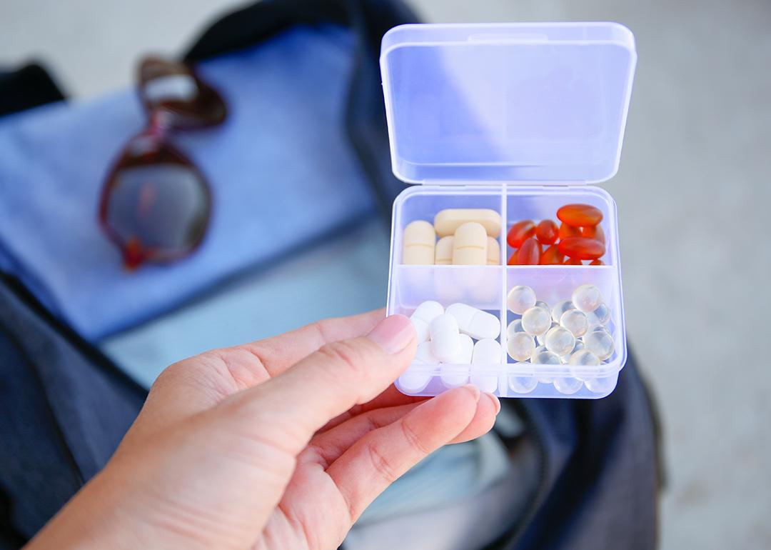 A box of pills with a travel bag in the background.