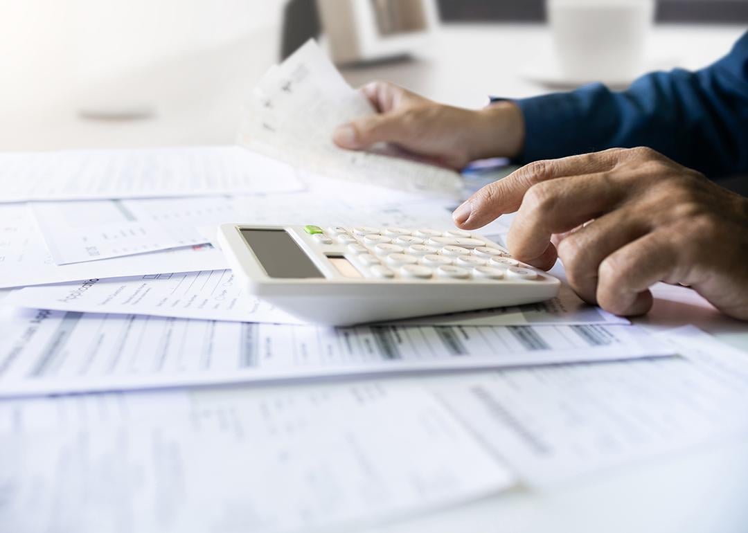 Man calculating figures from paper bills of expenses and other finance documents.