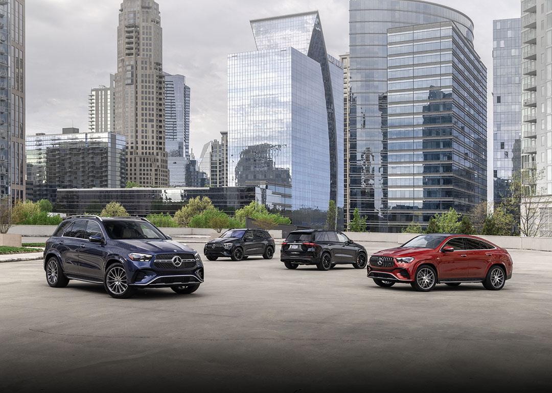 Four models in blue, black and red of the 2024 Mercedes-Benz GLE Coup parked on a rooftop with skyscrapers in the background.