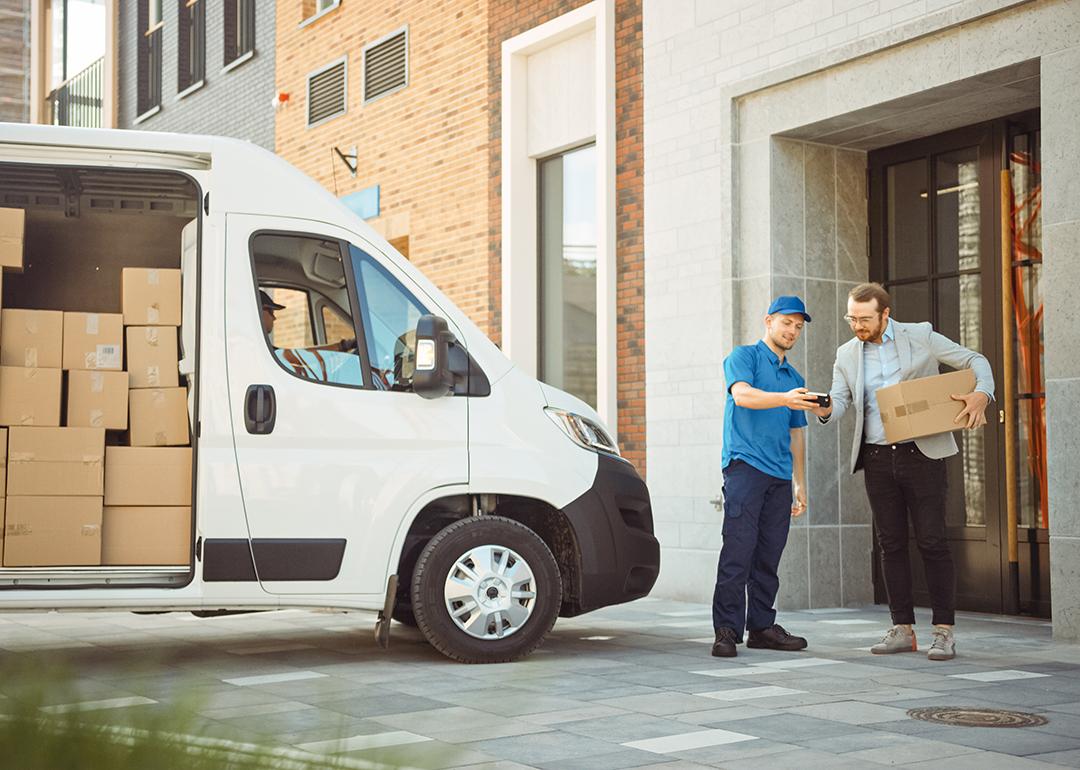 Delivery man gives postal package to its consignee in a business address.