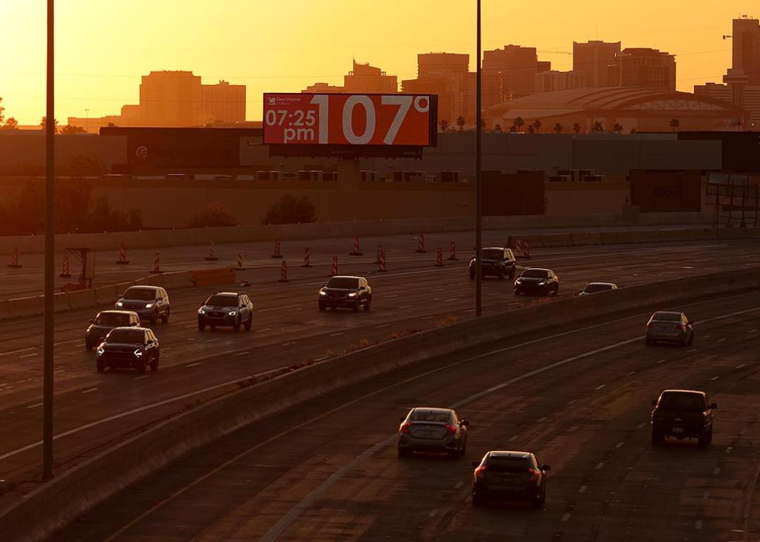 A billboard shows the current temperature over 100 degrees on June 05, 2024 in Phoenix, Arizona as drivers travel on the freeway in the foreground in the shadow of the setting sun.