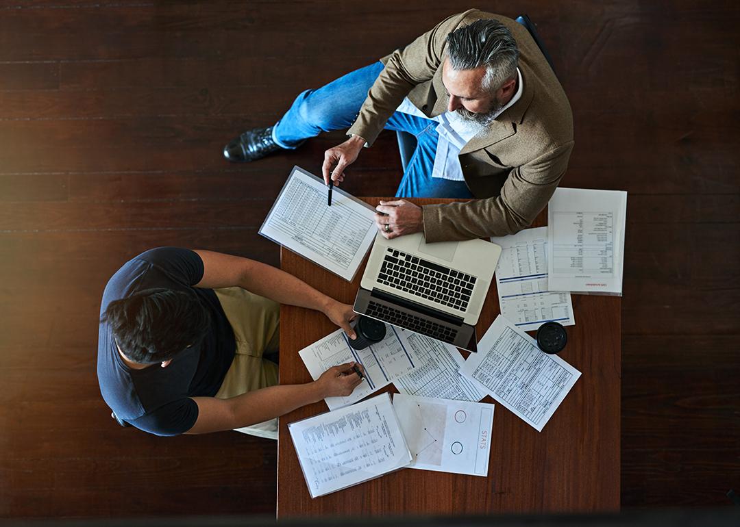 Two businessmen discussing strategy with accounting documents on their table.