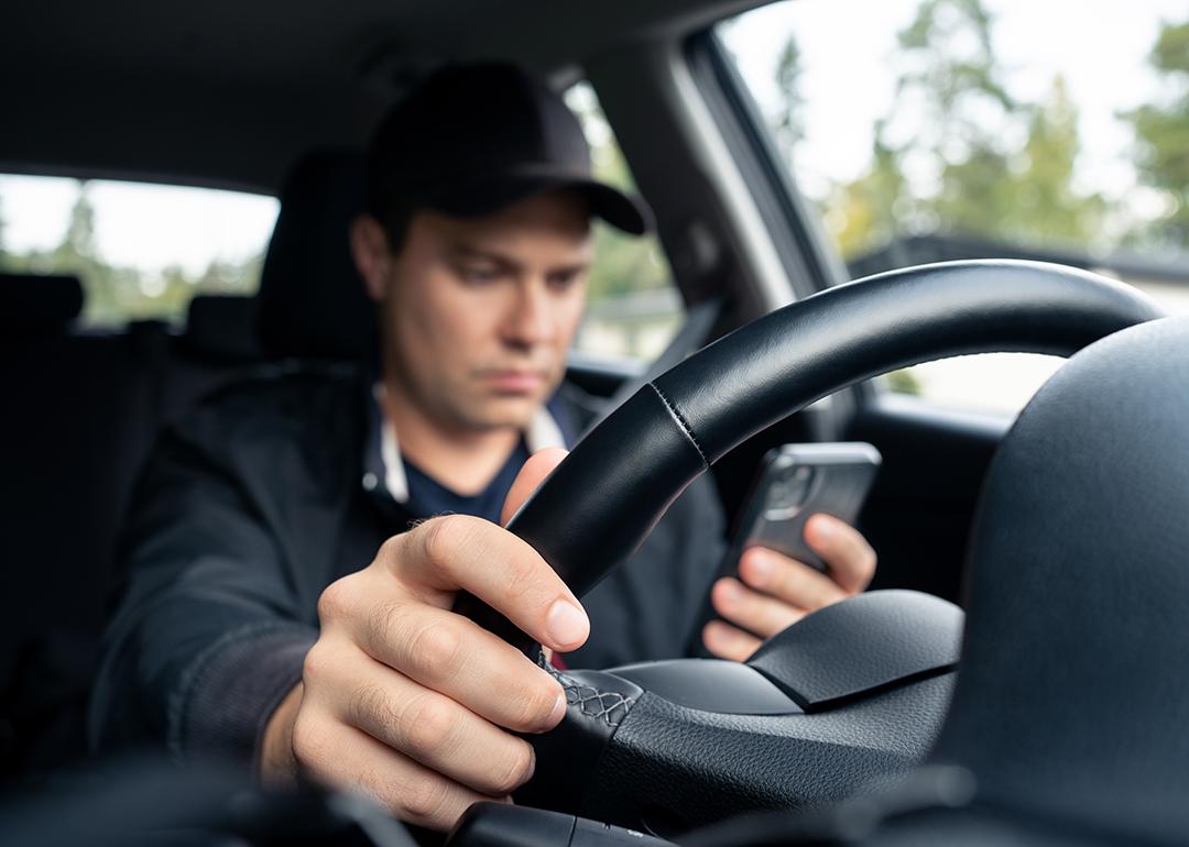 Man distracted texting on his smartphone while driving.