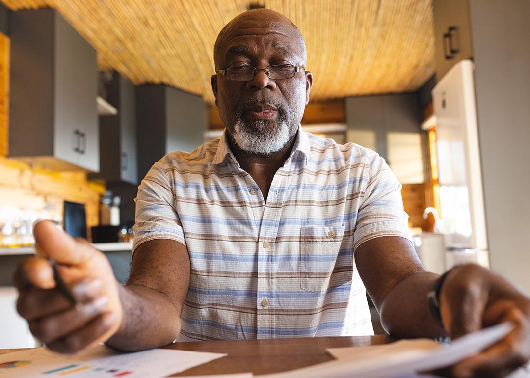 Senior man staring and signing finance documents.