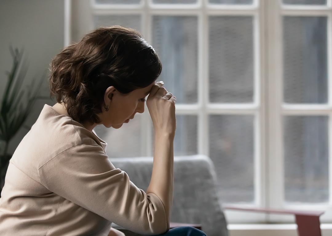 A middle aged woman sits in a worried state.